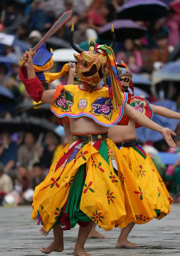 Masked cham dancer in a yellow skirt at a festival