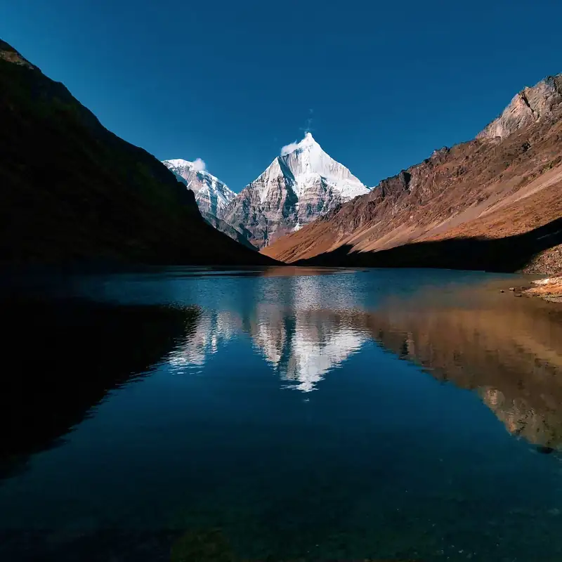 Jichu Drake peak reflected in a still alpine lake