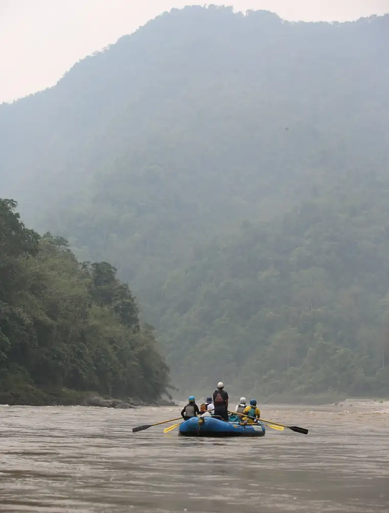 Rafting down a misty river between forested hills